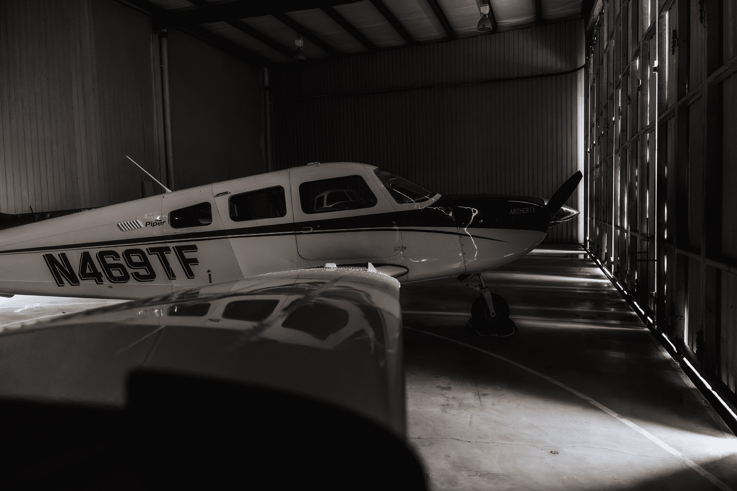 Piper aircraft inside the Texas Flight hangar with light falling across its wing