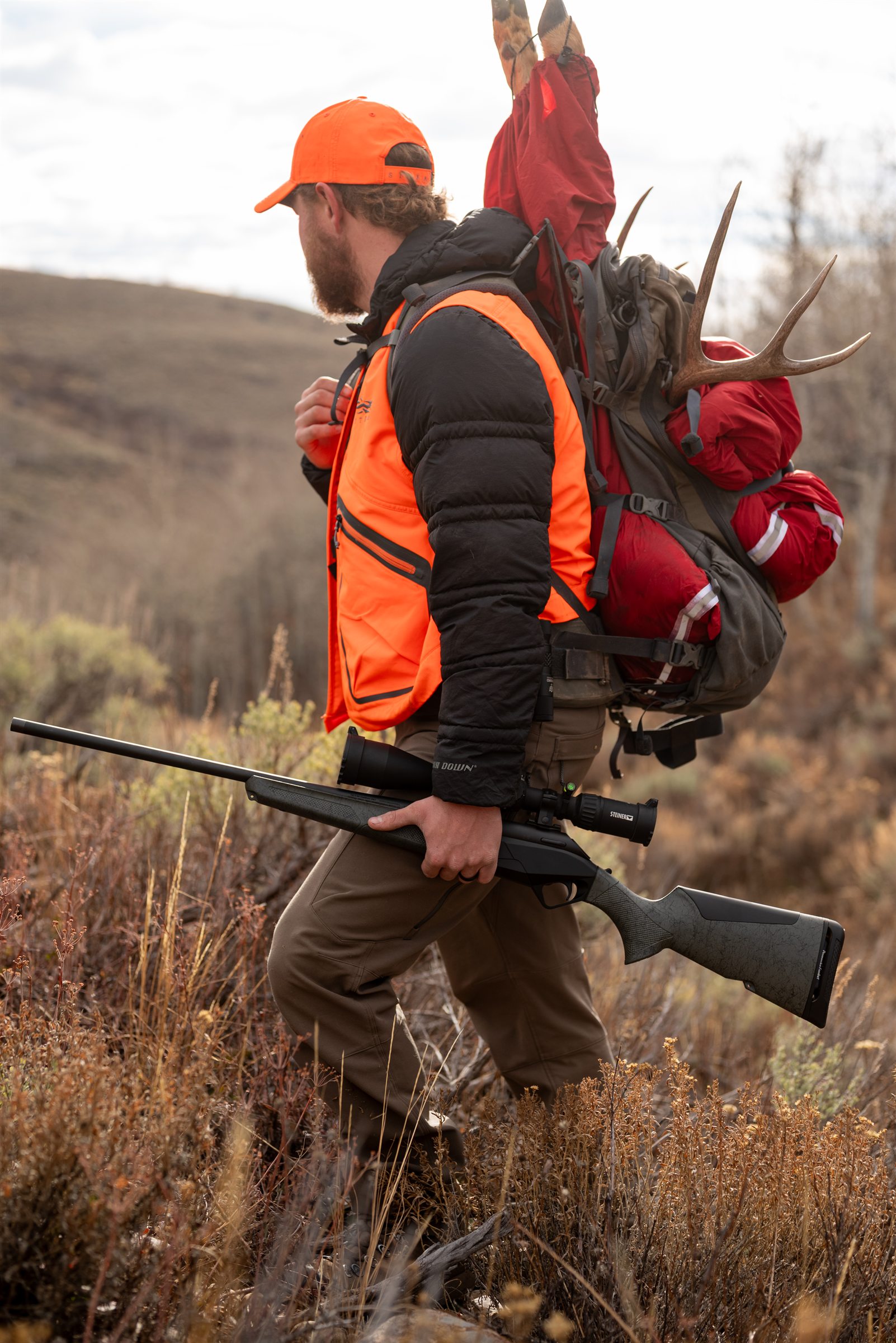 Outdoorsman hiking with hunting pack and rifle