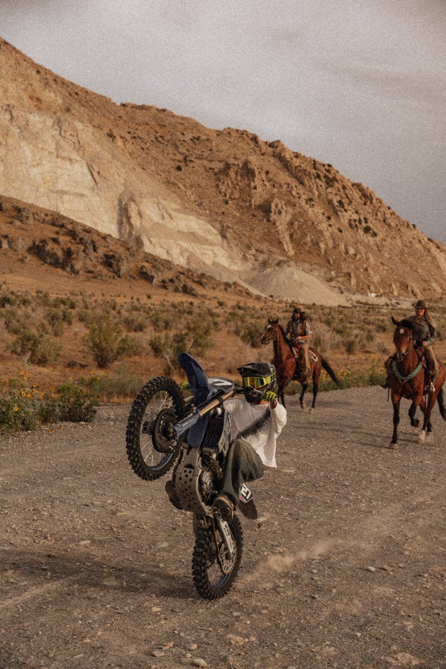 Dirt bike rider performing a wheelie on a country trail
