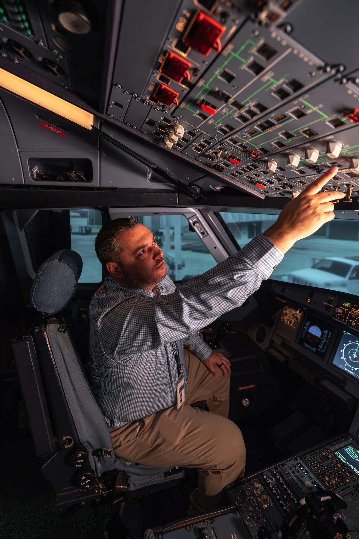 Flight simulator instructor demonstrating overhead controls