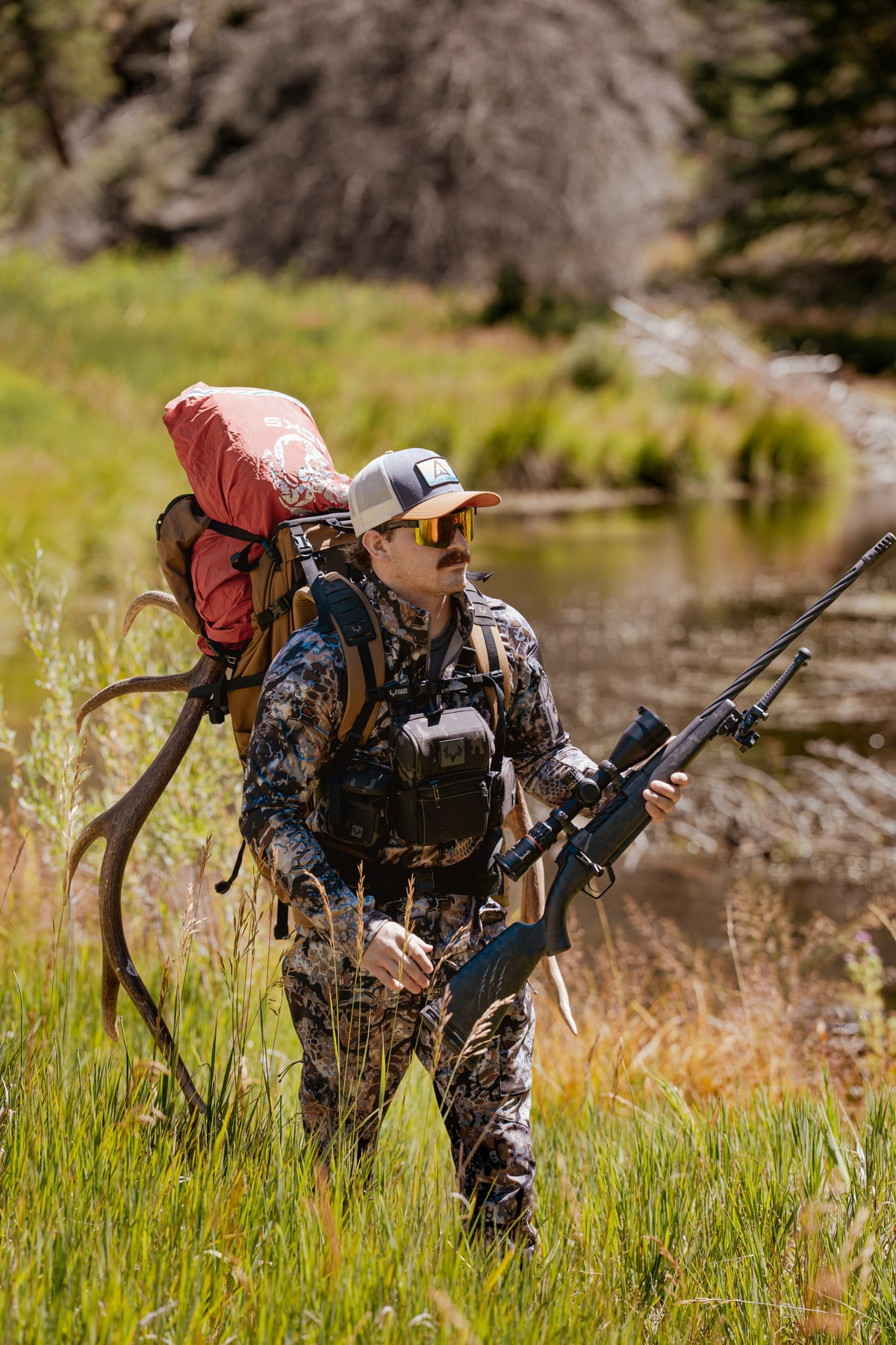 Hunter carrying a pack through a mountain landscape